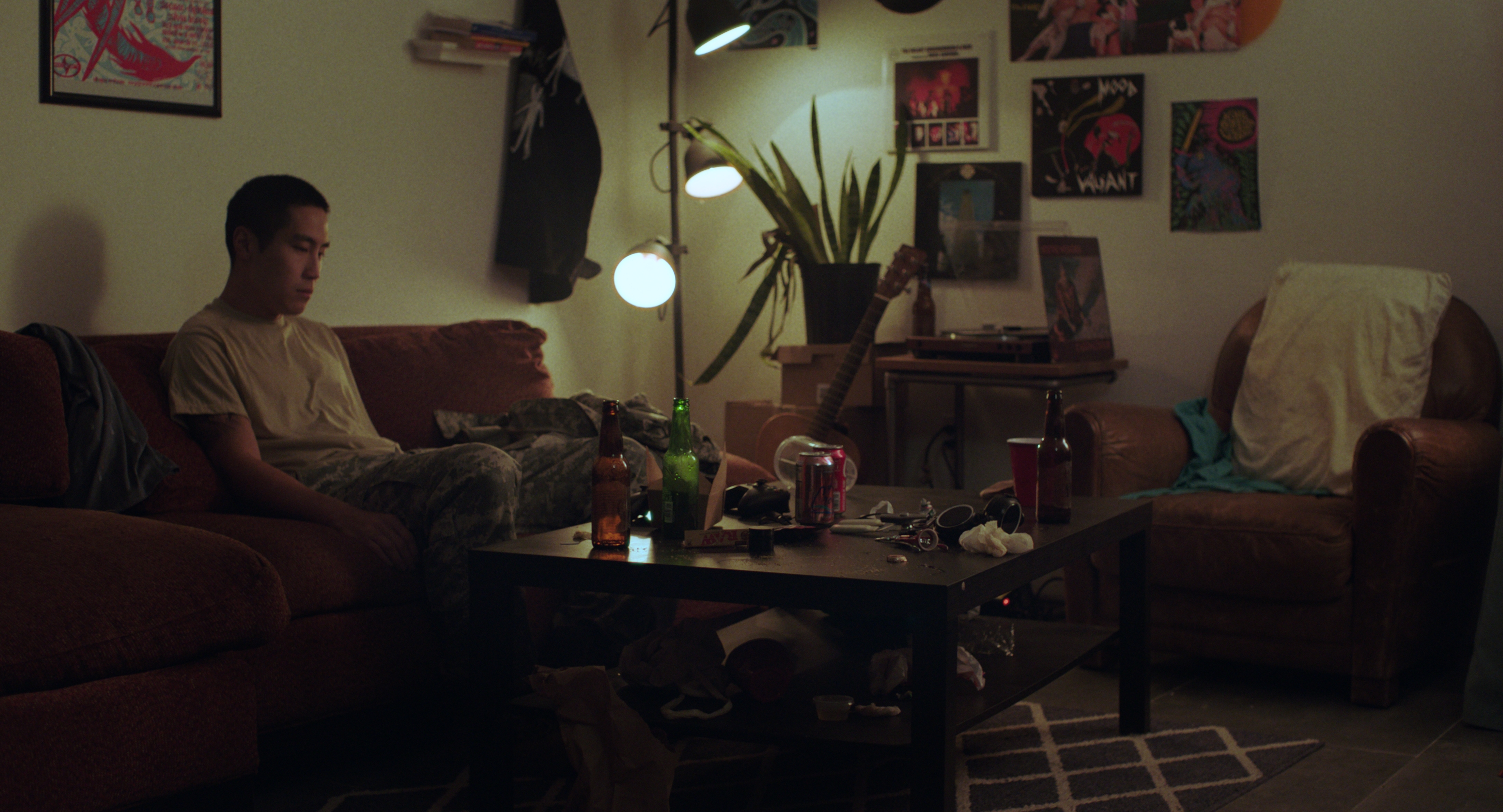 Film frame: The light in the scene was motivated by the practical lamp in the background, and the Astera Titan Tubes off-screen helped wrap the light to the actor's face. We could only dress this half of the room since the other half was used for the party scene, so the edges of the frame were the edges of the dressed set. In the color grade, I adjusted the light to be greener since I wanted the grime of his apartment to contrast with the warmth of his parents' house.