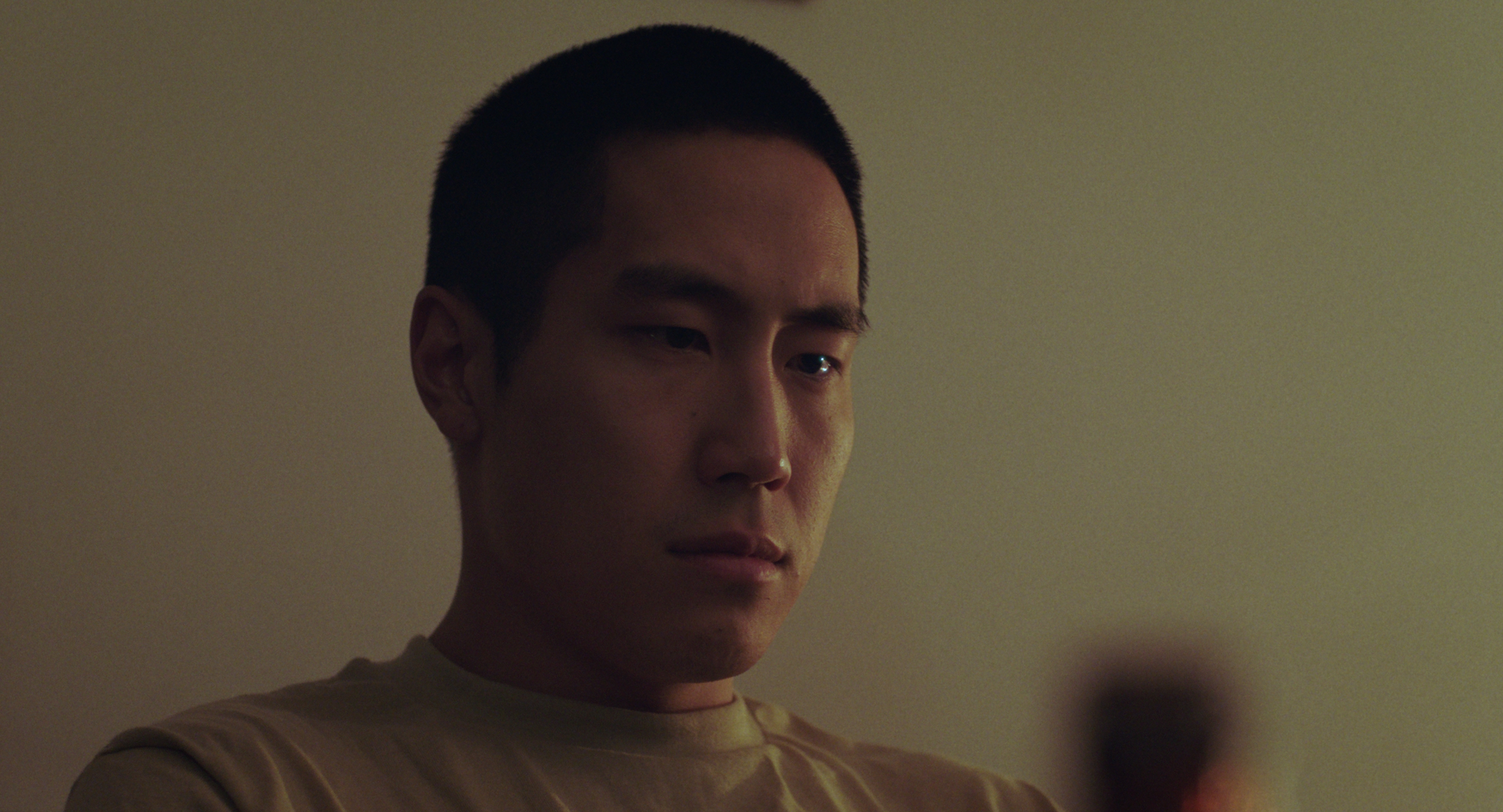 Film frame: We used a longer lens here (85mm) so that the silhouette of the beer bottle was dirty in the bottom-right of the frame. I love how the light caught the edge of Young Mazino's left eye, which accentuated his emotion here. Gianna Badiali, the cinematographer, did such a great job lighting the mood in this location. In post, I added a very small digital zoom-in, which helped transition from this scene to the final moment of the film.